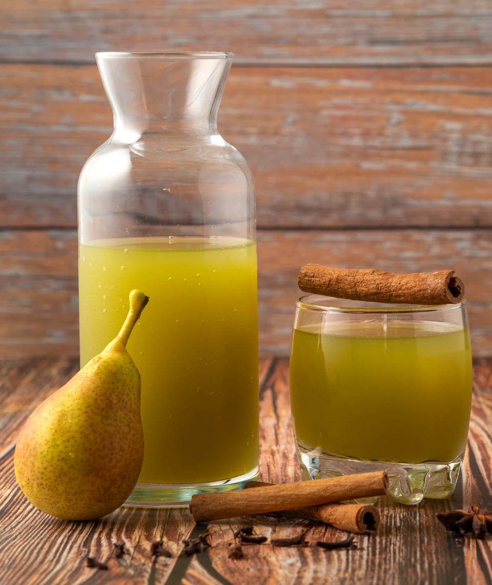 Naturalny sok gruszkowy z Żurawieckich Sadów – tłoczony na zimno, lokalny produkt Szklanka i karafka z naturalnym sokiem gruszkowym, obok świeża gruszka i laski cynamonu – Żurawieckie Sad