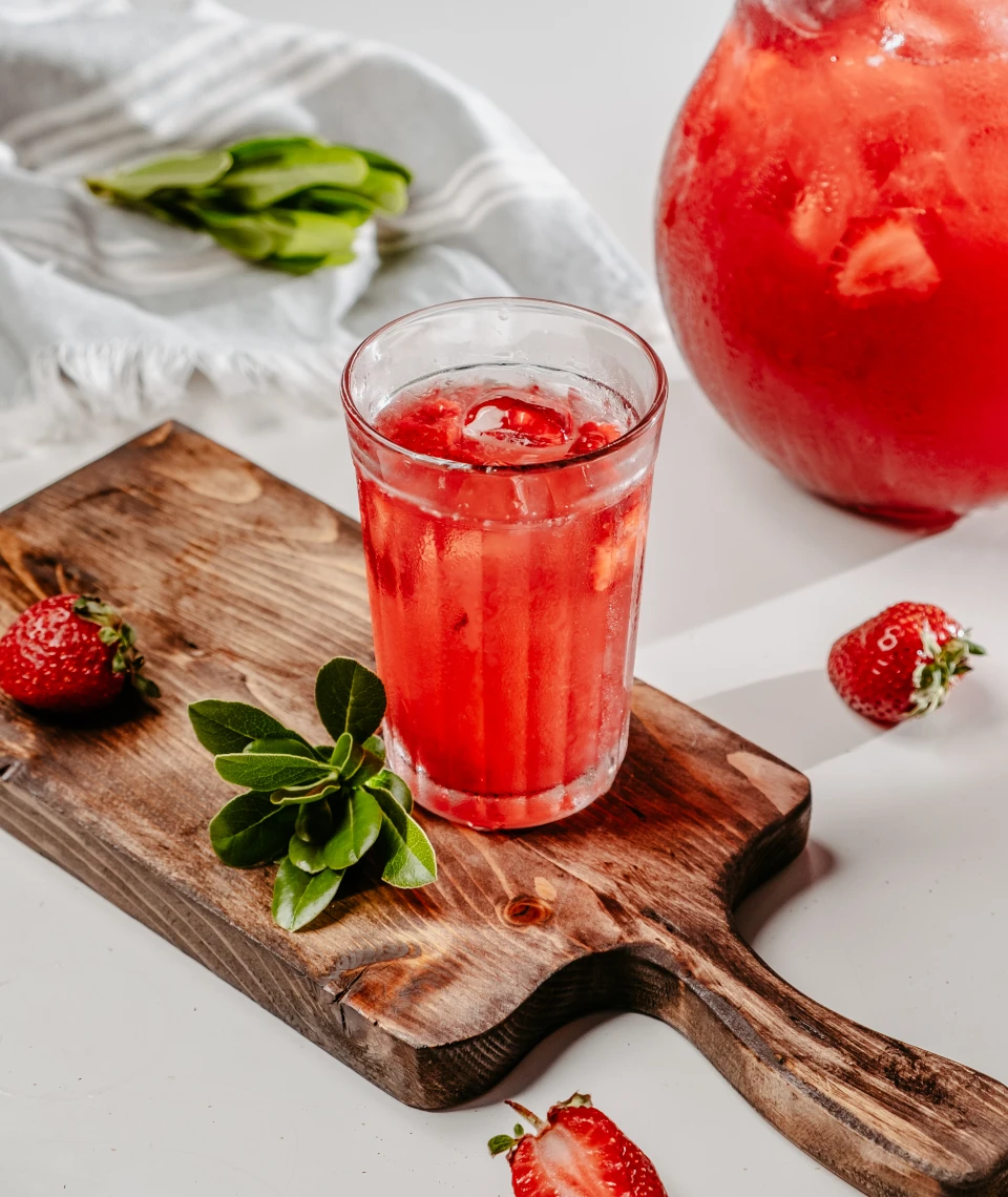 Naturalny sok truskawkowy z Żurawieckich Sadów – świeżość prosto z Żurawieckich Pól Szklanka schłodzonego soku truskawkowego z lodem i świeżymi truskawkami – produkt Żurawieckich Sadów